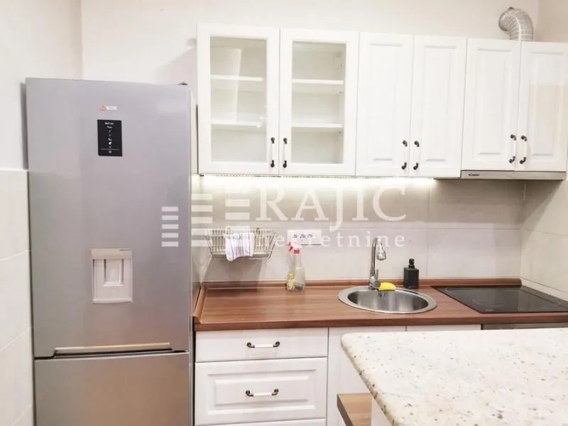 Small kitchen with white cabinets, refrigerator, and wooden countertops.