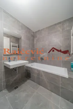 Moderno kupatilo obloženo sivim pločicama sa kadom i umivaonikom. - image 16