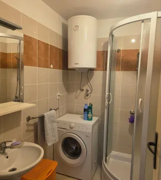 Smaller bathroom with a shower cabin, sink, washing machine, and water heater. - image 5