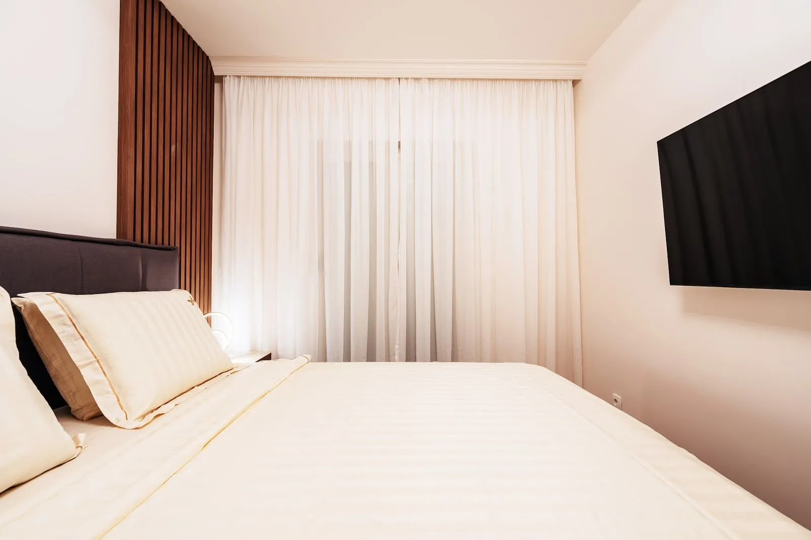 Tidy bedroom with a double bed and a wall-mounted TV.