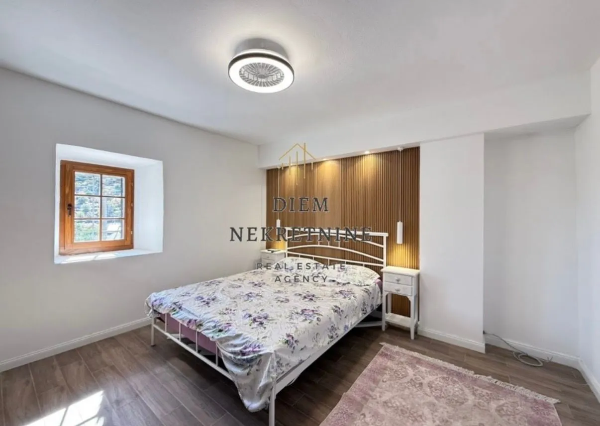 Bright bedroom with a double bed, wooden wall panel, and a window.