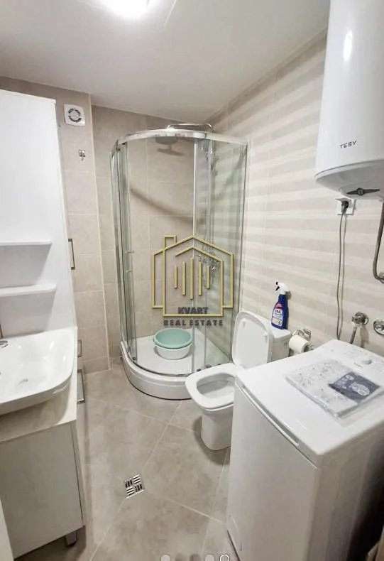 Bathroom equipped with a shower cabin, sink, toilet, and washing machine.