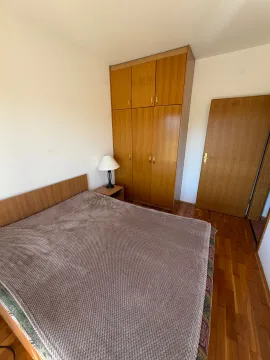 Spavaća soba sa bračnim krevetom, drvenim ormarom i noćnom lampom. - image 3