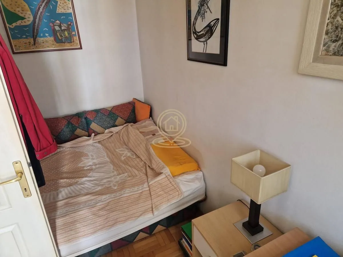 Small bedroom with a bed and a bedside table with a lamp.