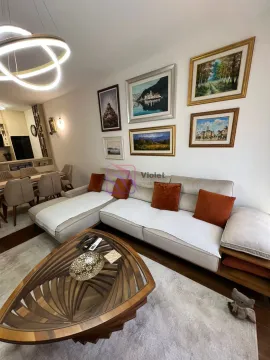 Living room with a sectional sofa, coffee table, and paintings on the wall. - image 13