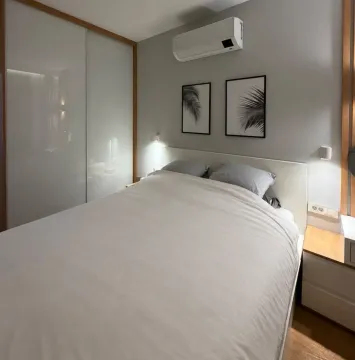 Modern bedroom with a double bed, built-in wardrobe, and air conditioning unit. - image 10