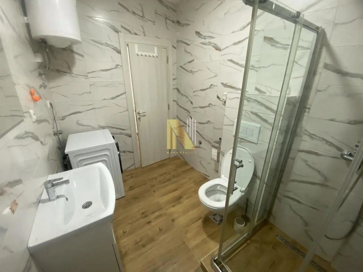 Modern bathroom with a walk-in shower, washbasin, and washing machine.