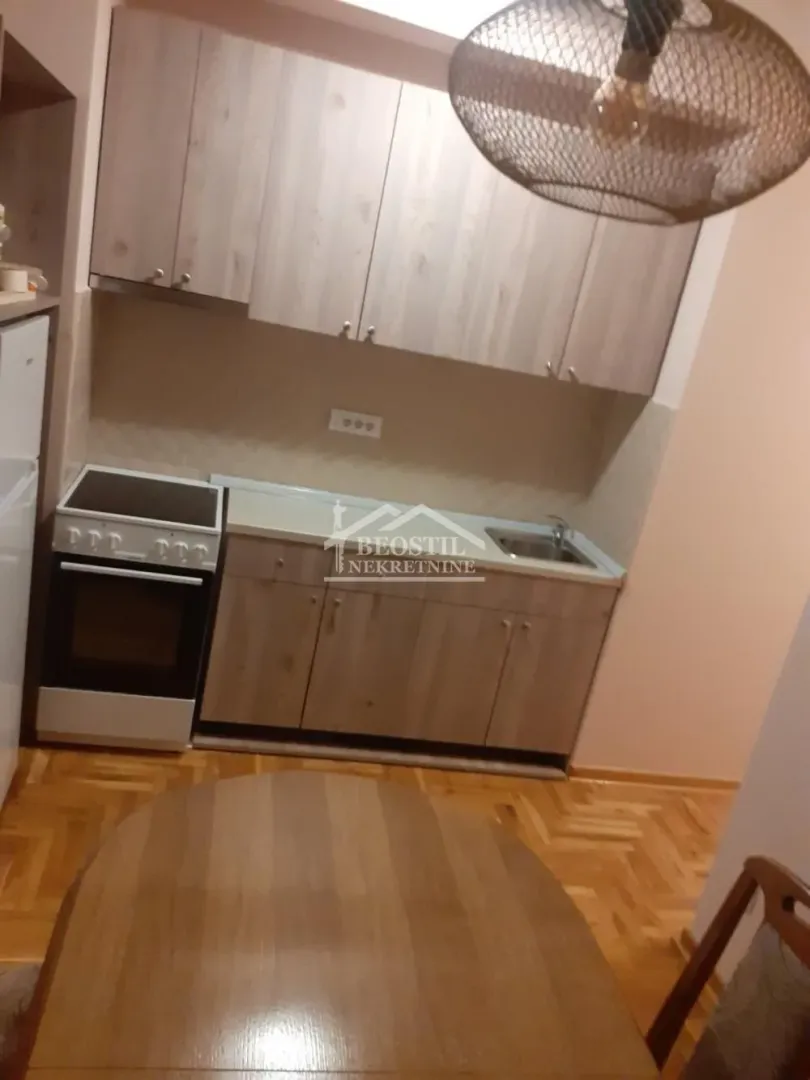 Manja kuhinja sa drvenim elementima, šporetom i sudoperom.