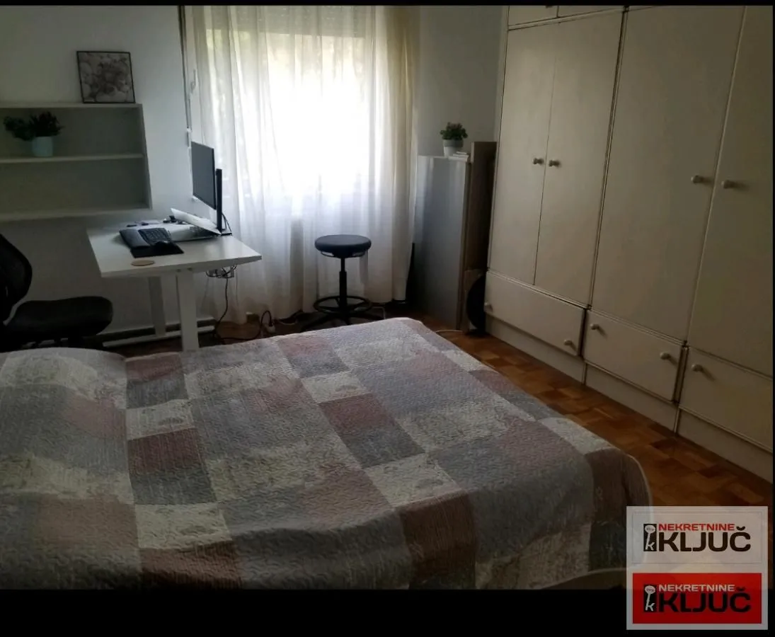Nameštena spavaća soba sa krevetom, garderoberom i radnim stolom.