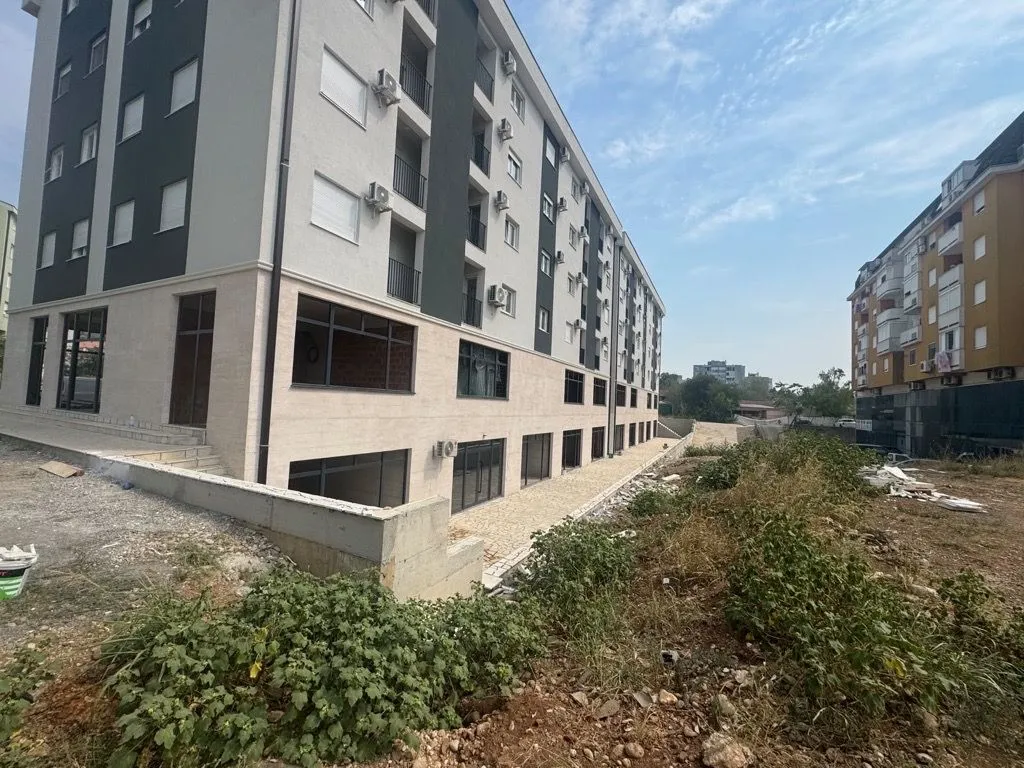 Pogled na spoljašnjost moderne stambene zgrade sa uređenim dvorištem.