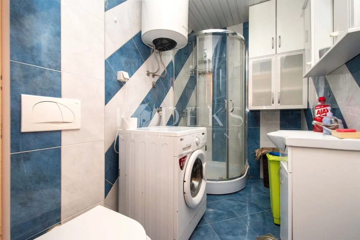 Bathroom equipped with a shower cabin, washing machine, and sanitary fixtures.