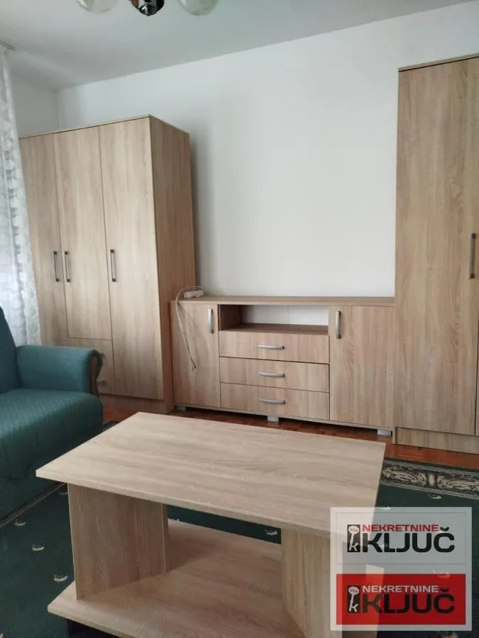 Dnevna soba sa drvenim ormarima, komodom i klub stočićem.