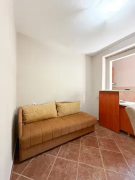 Manja dnevna soba sa braon trosjedom i pločicama na podu. - image 8