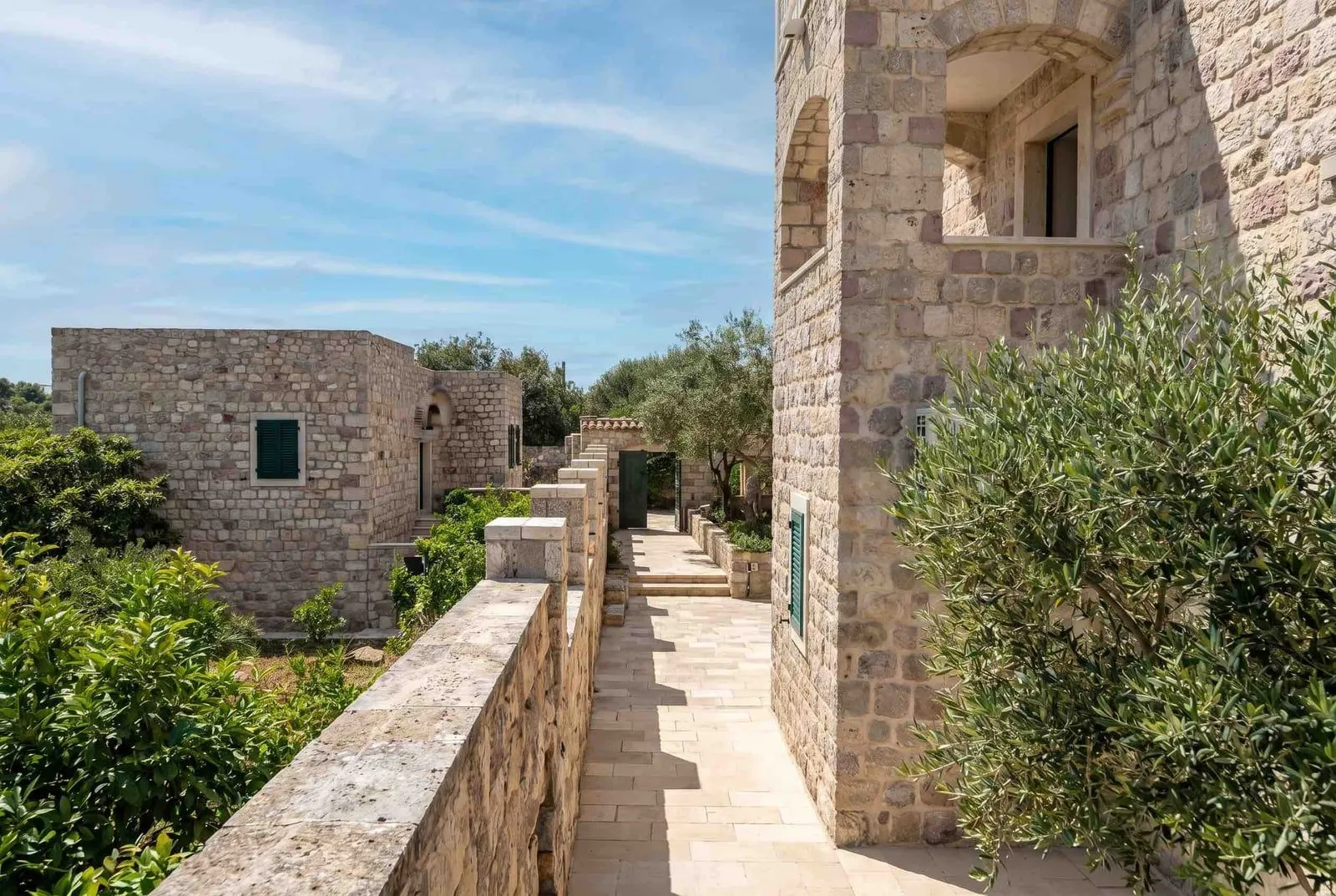 Tradicionalne kamene kuće sa popločanim dvorištem i mediteranskim biljkama.
