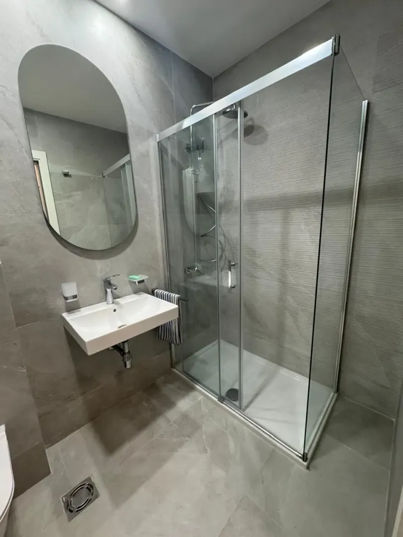 Modern bathroom with a shower cabin, sink, and large mirror.