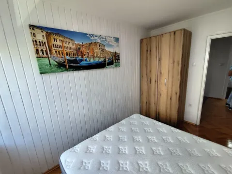 Spavaća soba sa krevetom, drvenim ormarom i zidom obloženim drvenim panelima. - image 11