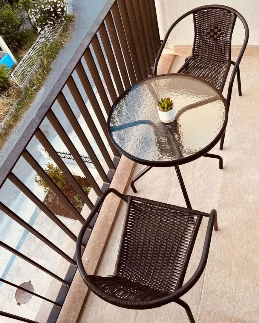 Manji namješteni balkon sa staklenim stočićem i dvije stolice.