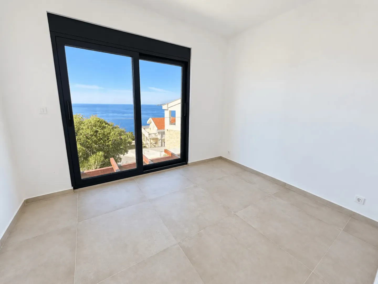 Empty room with large glass balcony doors and a sea view.