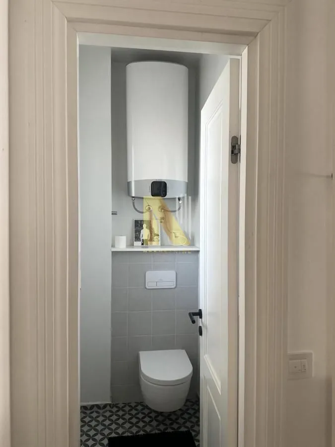 Pogled na kupatilo sa WC šoljom i bojlerom iz vrata.