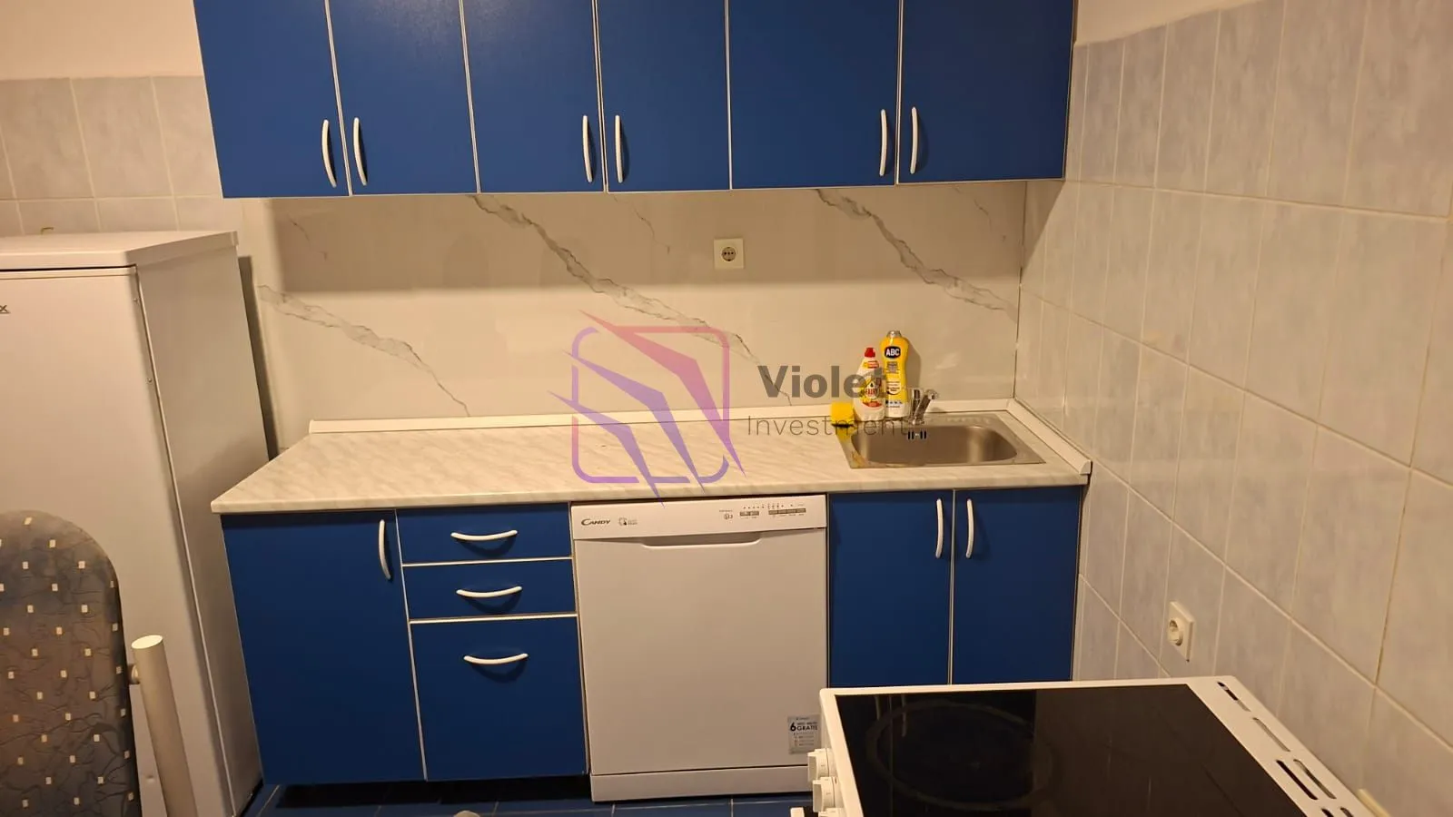 Small kitchen with blue cabinets and built-in home appliances.
