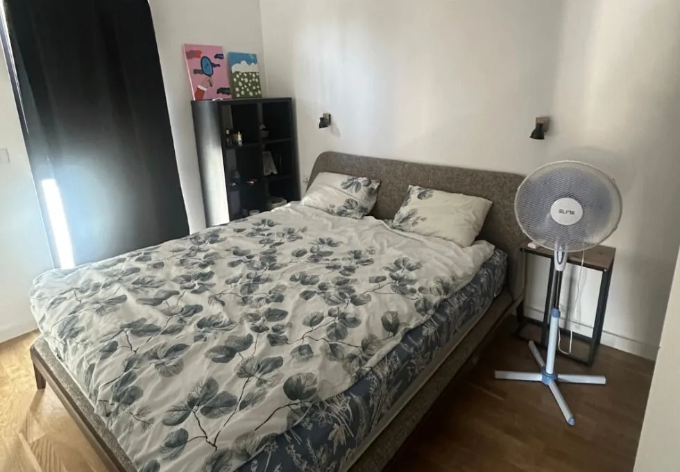 Namještena spavaća soba sa bračnim krevetom, policom i ventilatorom.