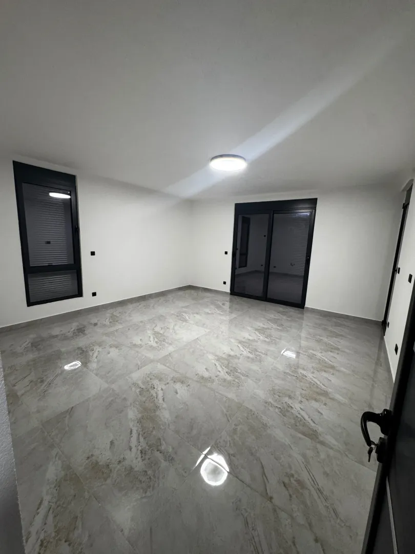 Empty room with glossy tiles and large windows.