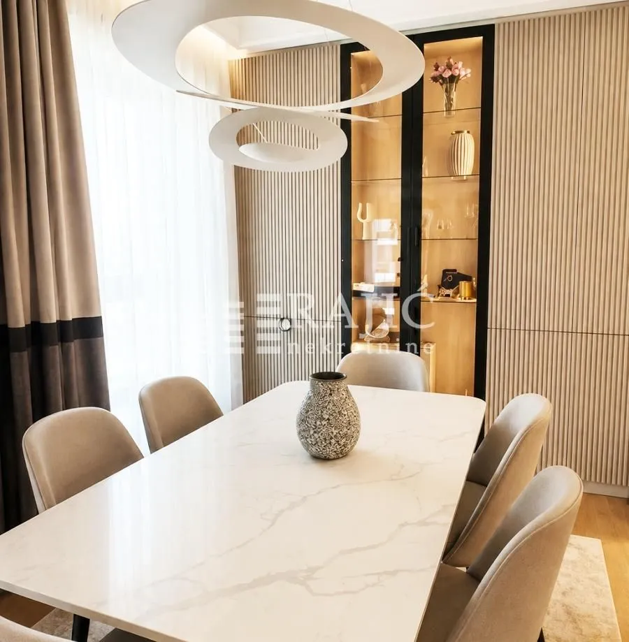 Modern dining room with a table, chairs, and a decorative chandelier.