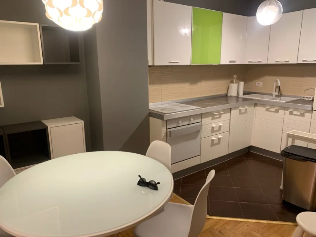 Modern kitchen with white units and a dining table.
