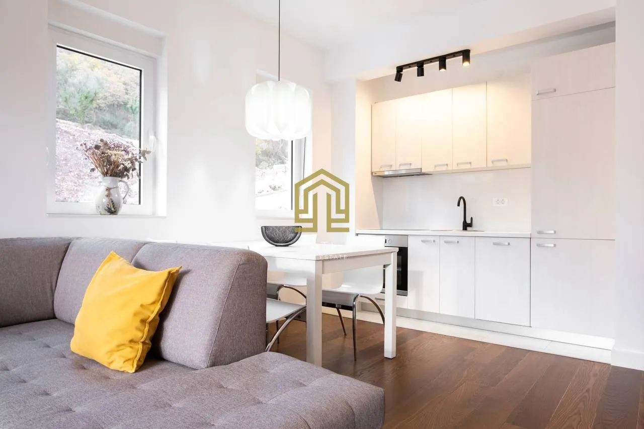 Living room with sofa and dining area connected to the kitchen.