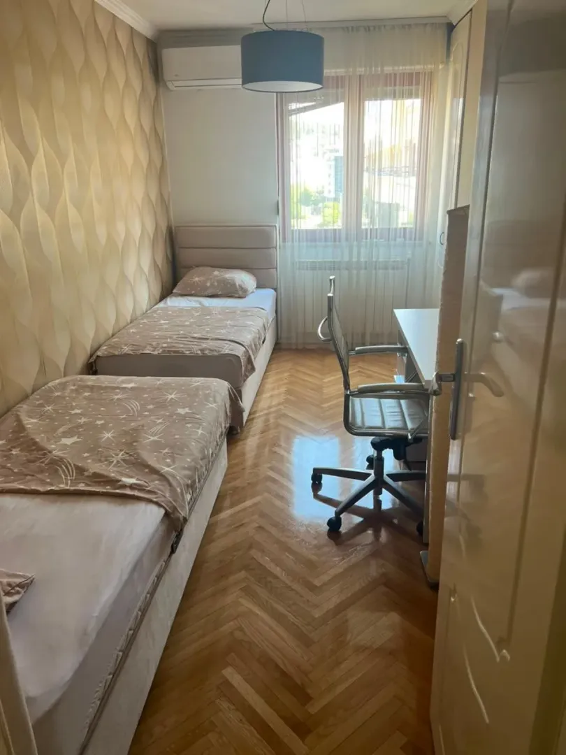 Spavaća soba sa dva kreveta i radnim stolom.