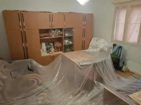 Dnevna soba sa drvenim ormarima i nameštajem prekrivenim najlonom. - image 6