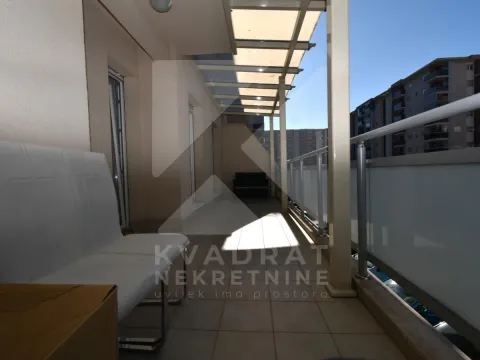Prostrana natkrivena terasa sa garniturom za sjedenje i pogledom na okolne zgrade. - image 12