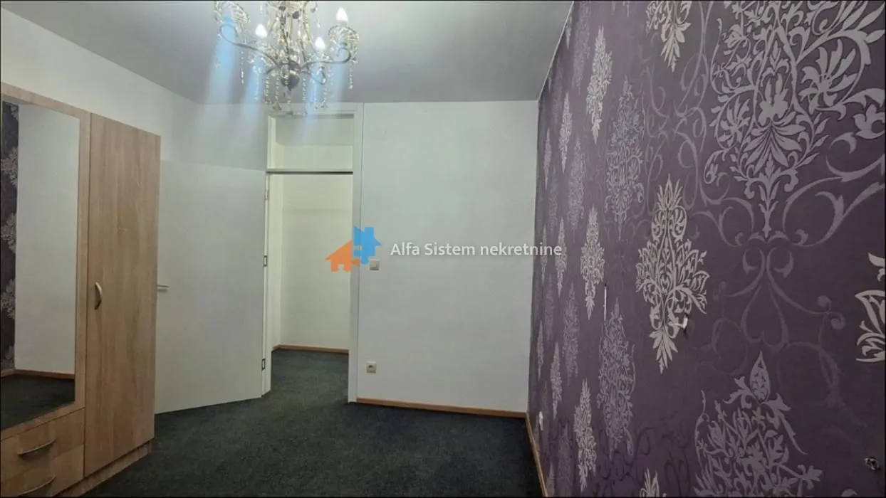 Furnished bedroom with a wardrobe and decorative wallpaper.