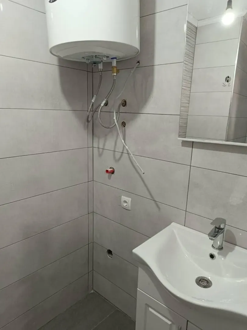 Small bathroom with a sink, mirror, and water heater.