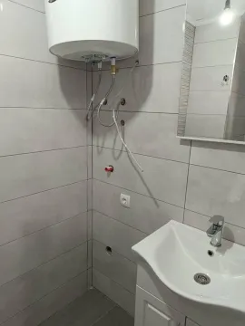 Small bathroom with a sink, mirror, and water heater. - image 5