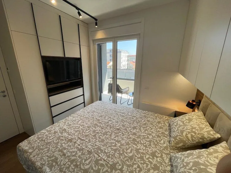 Modern bedroom with a double bed, built-in wardrobe, television, and access to the terrace.