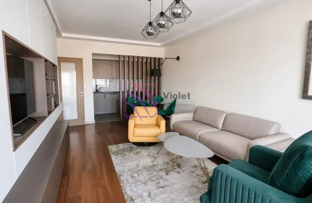 Living room with sofa set, TV unit, and a view of the dining area and kitchen.