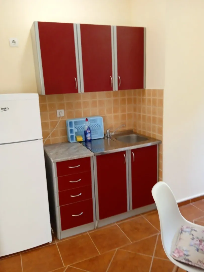 Small kitchen with red cabinets and a white refrigerator.