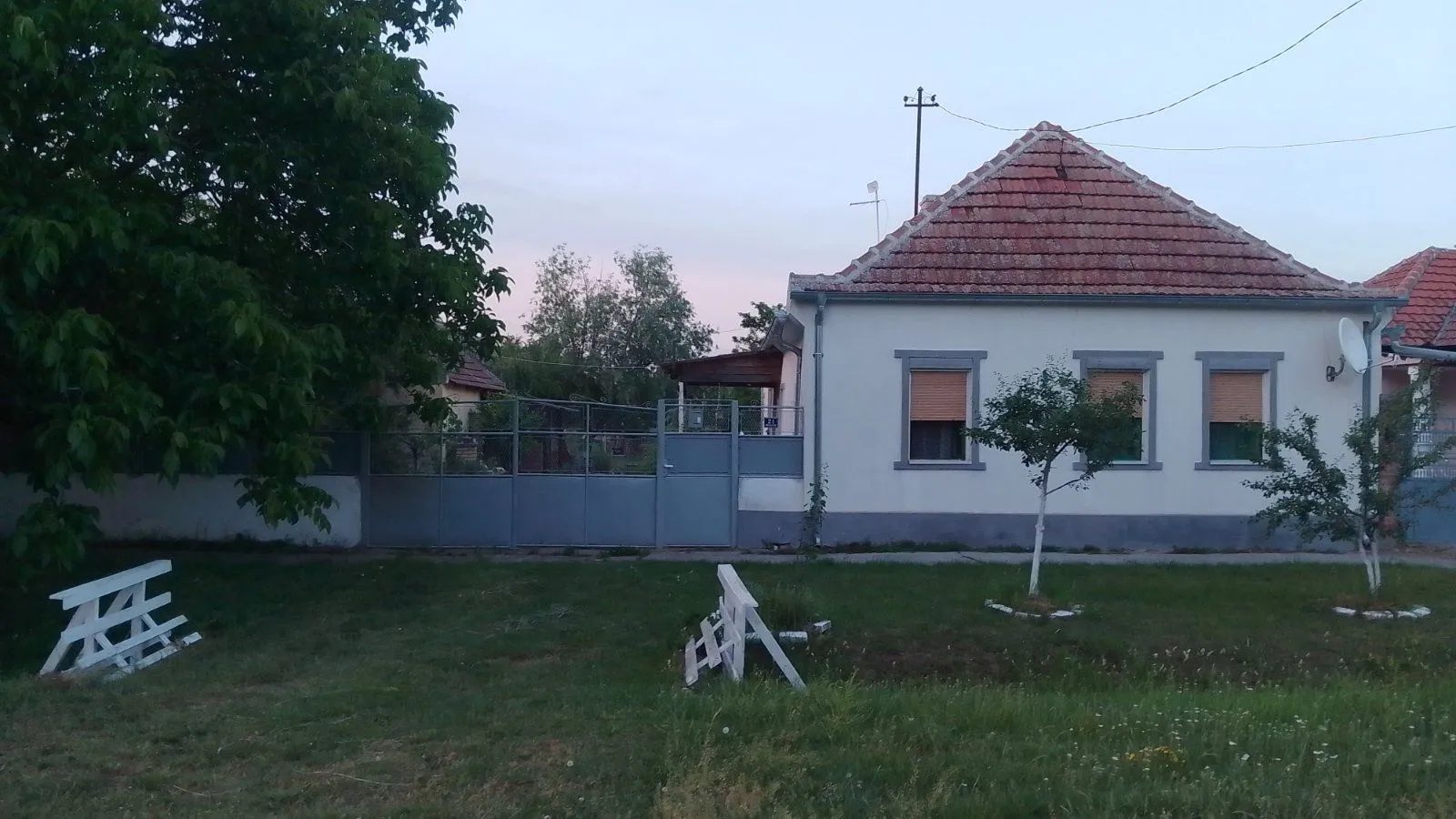 Pogled na kuću sa dvorištem i ogradom.