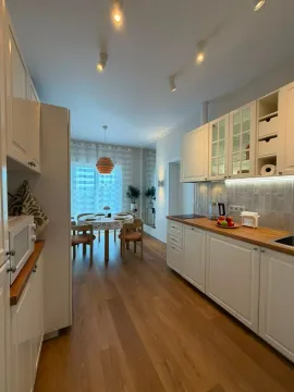 Moderna bijela kuhinja sa drvenom radnom površinom i trpezarijom u nastavku. - image 4