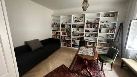 Dnevna soba sa velikom bibliotekom, crnim kaučem i radnim stolom. - image 9