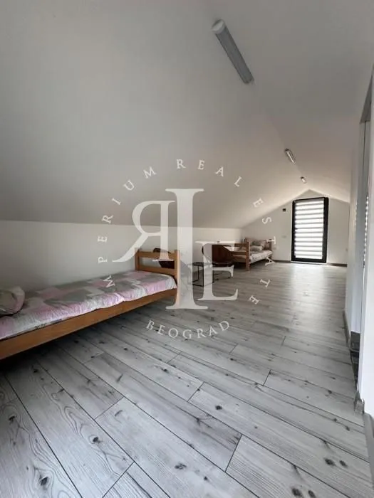 Attic furnished as a bedroom with beds and wooden flooring.