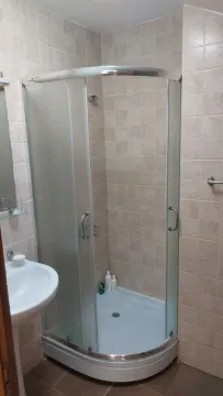 Manje kupatilo sa tuš kabinom i umivaonikom obloženo keramičkim pločicama u neutralnim tonovima. - image 4