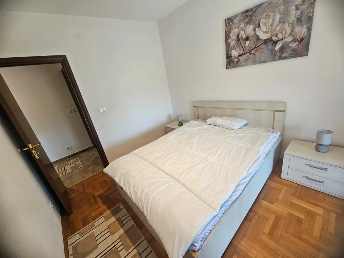 Namještena spavaća soba sa bračnim krevetom i noćnim stočićima.