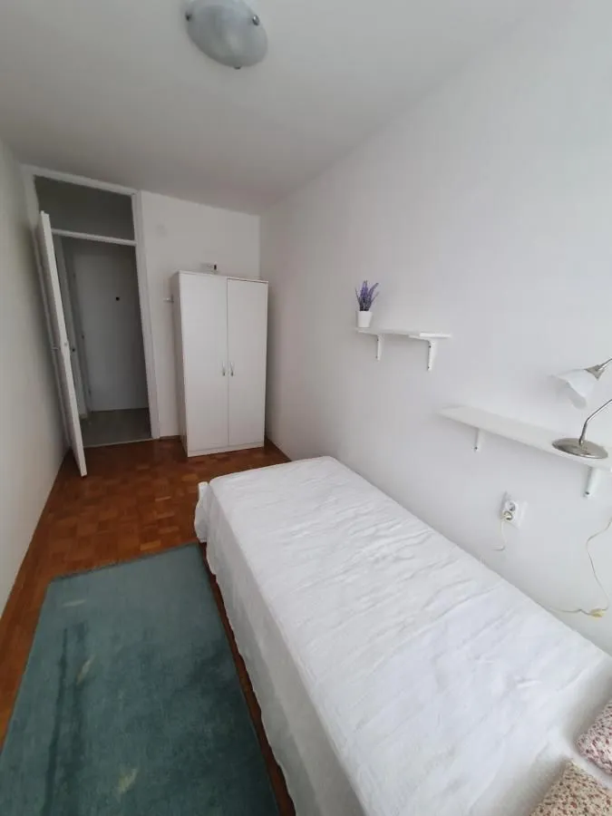 Manja spavaća soba sa krevetom, ormarom i drvenim podom.