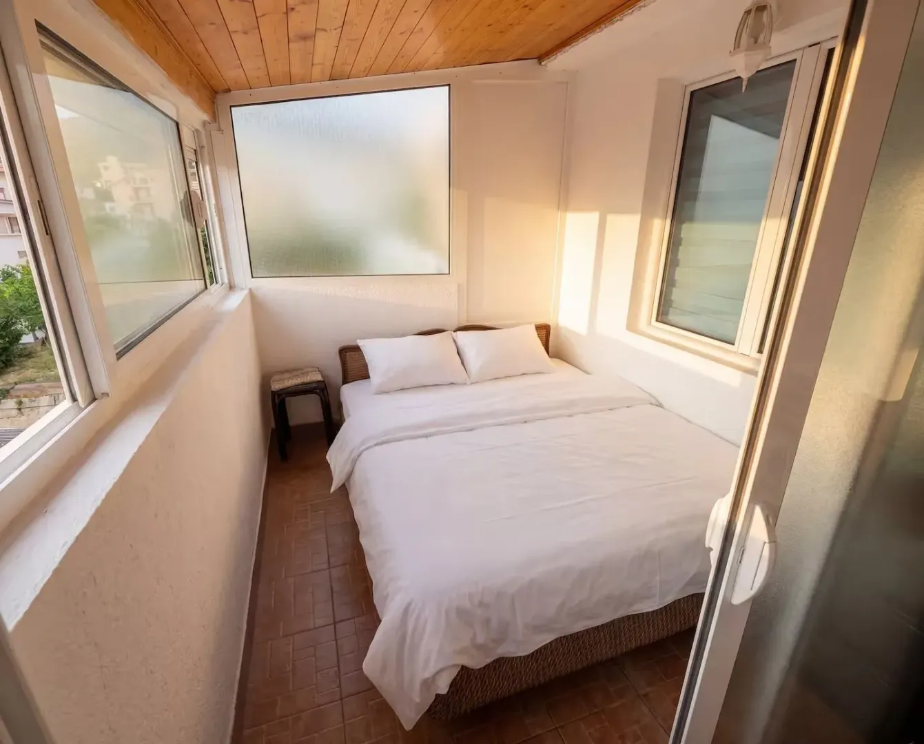 Small bedroom with a double bed and large windows.