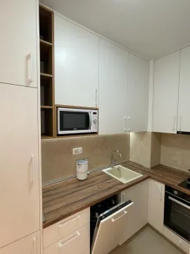 Modern kitchen with white cabinetry, built-in appliances, and a wooden countertop. - image 4