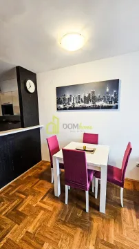 Dining area with a white table and pink chairs against a wall with a cityscape painting. - image 6