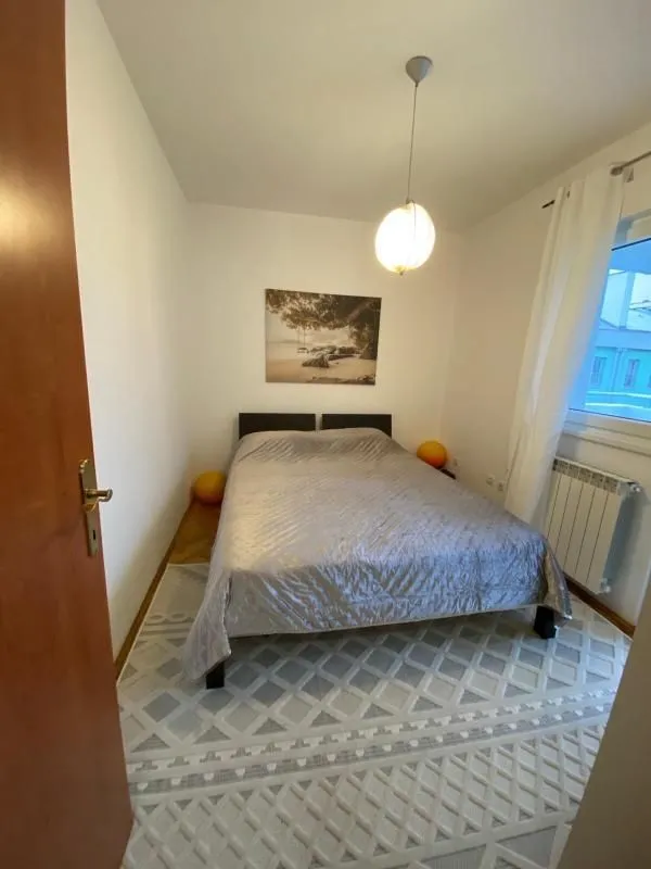 Spavaća soba sa bračnim krevetom, tepihom i prozorom.