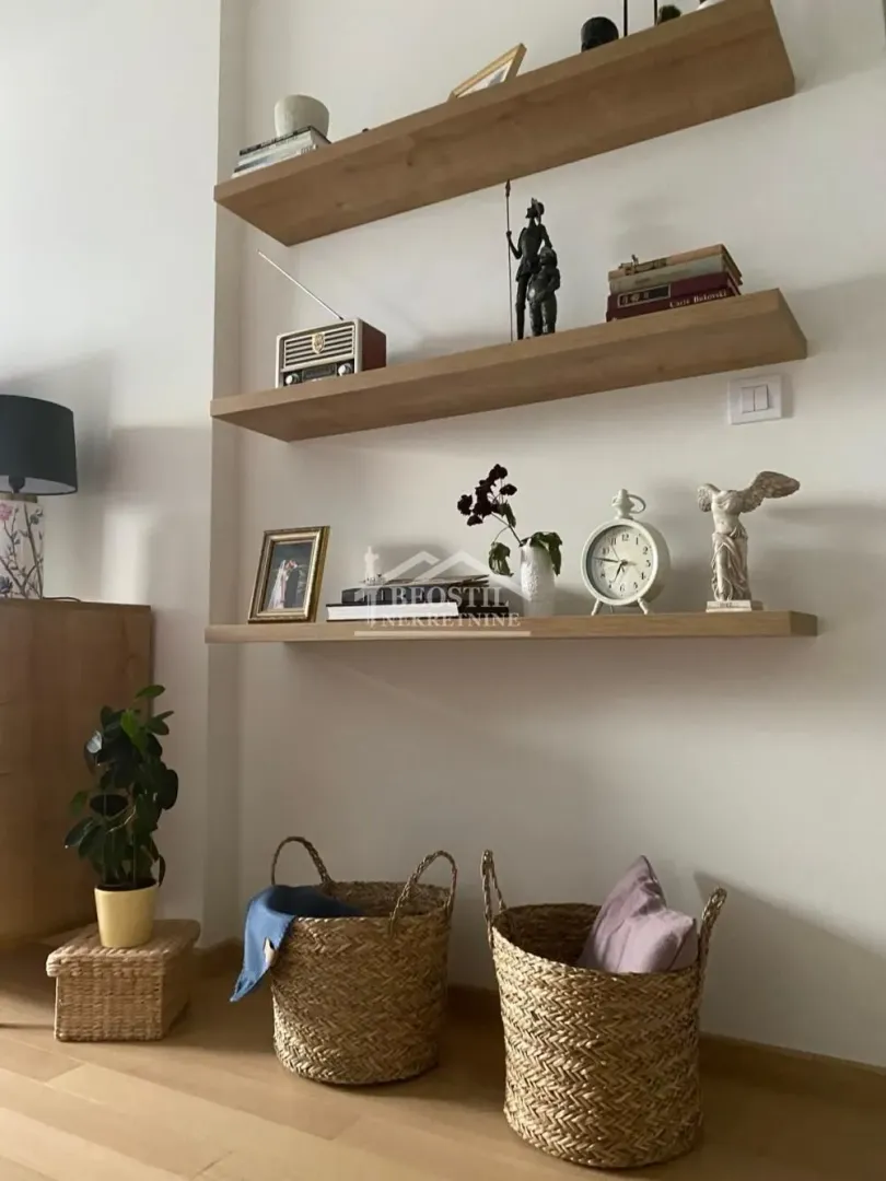 Detalj sa drvenim zidnim policama i ukrasnim predmetima u dnevnoj sobi.